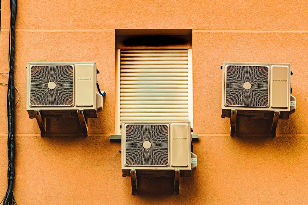 Technician examining a residential HVAC outdoor unit in a backyard with tools on the ground nearby.