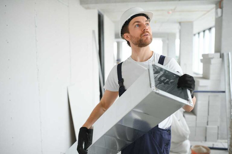 A close-up of a person adjusting a digital home thermostat on a wall in a residential living room.